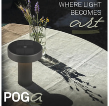 Solární stolní lampa na světlém, prostřeném zahradním stole s vázou květin a Poga Logo.