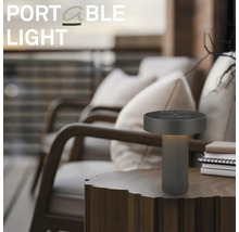 Moderní přenosná stolní LED lampa na dřevěném stole ve venkovním prostoru s křesly.