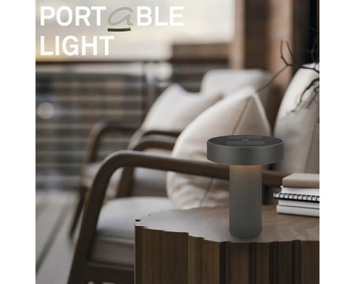 Moderní přenosná stolní LED lampa na dřevěném stole ve venkovním prostoru s křesly.