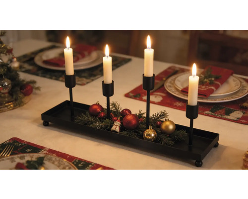 Adventní svícen z černého kovu se čtyřmi držáky na svíčky, zdobený jedlovým chvojím a vánočními ozdobami na slavnostně prostřeném stole.