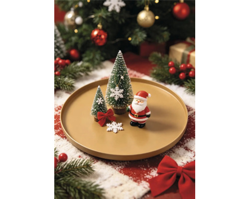 Vánoční dekorace na talíři s figurkou Santa Clause, dvěma miniaturními stromky a sněhovými vločkami na světlém svátečním pozadí.
