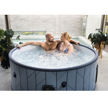 Pár relaxuje v kulaté nafukovací vířivce s geometrickým vzorem na moderní terase.