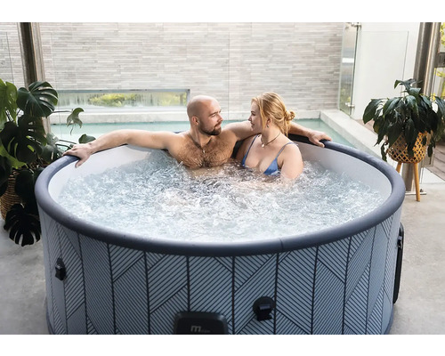 Pár relaxuje v kulaté nafukovací vířivce s geometrickým vzorem na moderní terase.