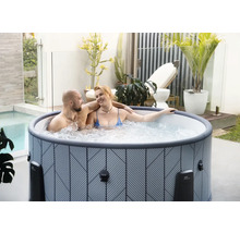 Nafukovací vířivka s geometrickým vzorem na světlé terase s rostlinami a párem.