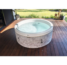 Kulatá vířivka se šedou vzorovanou vnější stěnou na dřevěné terase v zahradě.