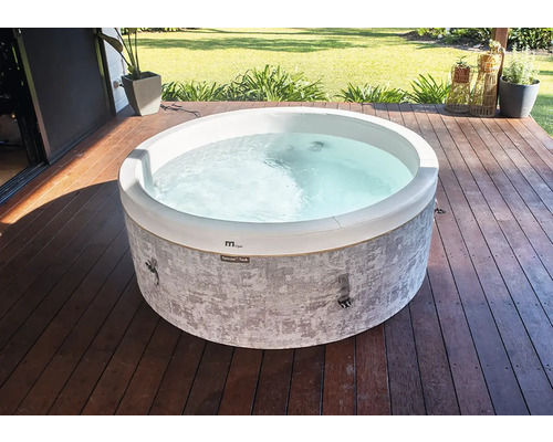 Kulatá vířivka se šedou vzorovanou vnější stěnou na dřevěné terase v zahradě.