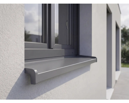 Venkovní hliníkový parapet instalovaný na omítnuté fasádě pod oknem.