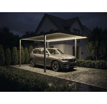 Moderní hliníkový přístřešek na auto s integrovaným LED osvětlením, lamelovou střechou a zaparkovaným SUV na dlážděné cestě v noci.