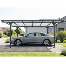 Samostatně stojící moderní přístřešek pro auto s kovovým rámem a průsvitnými střešními panely, chránící auto na příjezdové cestě.