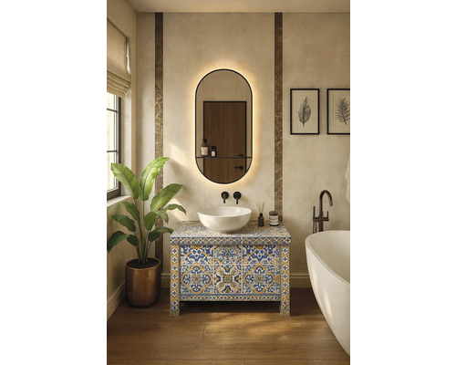 Moderní koupelna s dlaždicovou skříňkou pod umyvadlo, umyvadlem na desku, oválným zrcadlem s osvětlením, volně stojící vanou a rostlinou.