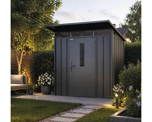 Moderní kovový zahradní domek s pultovou střechou, dveřmi s oknem a nadsvětlíky v zahradě s dlážděným chodníkem a rostlinami.