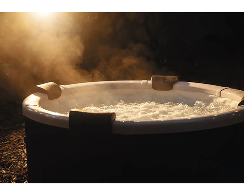 Kulatá nafukovací vířivka s bublající vodou, opěrkami hlavy a stoupající párou venku v noci.