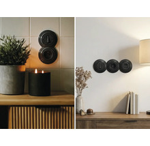 Černé retro vypínače a zásuvky v kulatém bakelitovém designu namontované na kachličkové stěně a hladké stěně v interiéru.