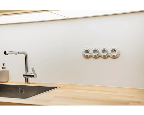 Moderní kuchyně s nerezovým dřezem, chromovanou baterií, dřevěnou pracovní deskou a čtyřnásobnou zásuvkou.