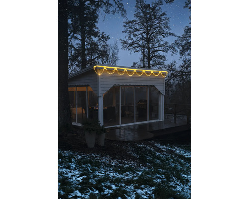 LED světelný déšť s teplým bílým světlem na moderním zahradním domku v zimním nočním prostředí.