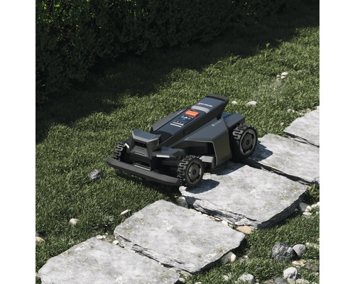 Robotická sekačka Segway Navimow přejíždí kamenné nášlapy v zahradě s trávníkem.