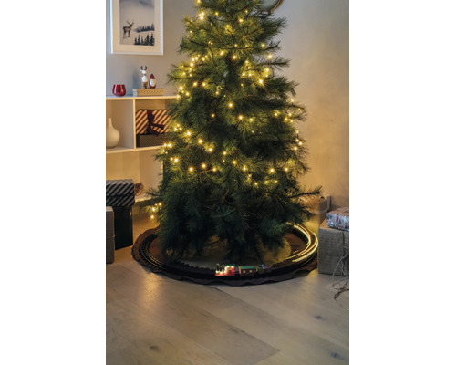 Umělý vánoční stromek s LED světly a modelem vláčku na kolejích pod ním, obklopený dárky.