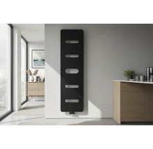 Moderní vertikální designový radiátor v černé barvě s horizontálními otvory na bílé stěně ve světlé minimalistické místnosti.