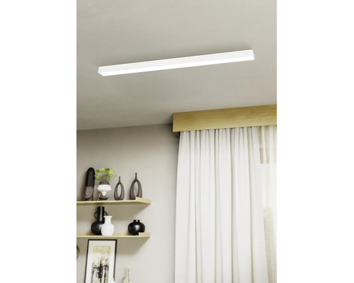 Moderní stropní LED svítidlo v plochém obdélníkovém tvaru namontované na světlém stropě v jasném obývacím pokoji s policemi a závěsy.