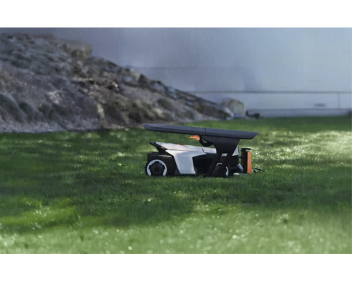 Moderní ochranná garáž pro robotickou sekačku na trávníku za deště, funkční design pro ochranu před povětrnostními vlivy.