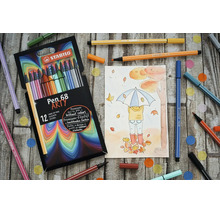 Sada 12 fixů STABILO Pen 68 Arty s podzimní kresbou a rozházenými pery na dřevěném podkladu.