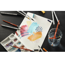 Fixy STABILO Creative Tips, štětce, míchací paleta a abstraktní kresba na papíře na tmavé pracovní ploše.