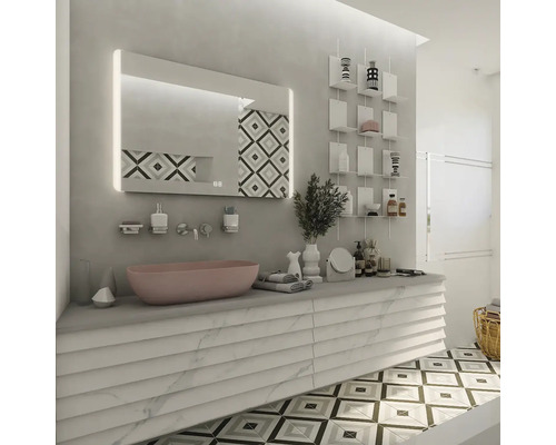 Moderní koupelna s růžovým umyvadlem na desku na bílé skříňce s mramorovým efektem, osvětleným zrcadlem a geometrickou dlažbou.