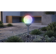 Solární zahradní kulové svítidlo s vícebarevným RGB osvětlením, na zapichovacím hrotu v záhonu s oblázky a rostlinami.
