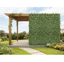 Dřevěná pergola s umělým živým plotem jako ochranou soukromí ve světlé, organizované zahradě s květinami a kamennou cestou.