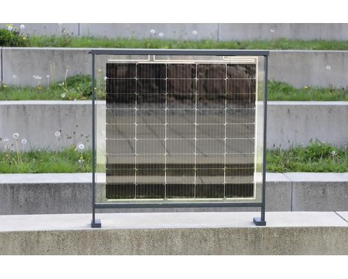 Poloprůhledný solární modul v tmavě šedém kovovém rámu pro balkon nebo plot, stojící na betonovém povrchu.
