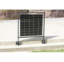 Solární panel integrovaný do černého kovového zábradlí, namontovaný na kamenné terase před zdí z přírodního kamene.
