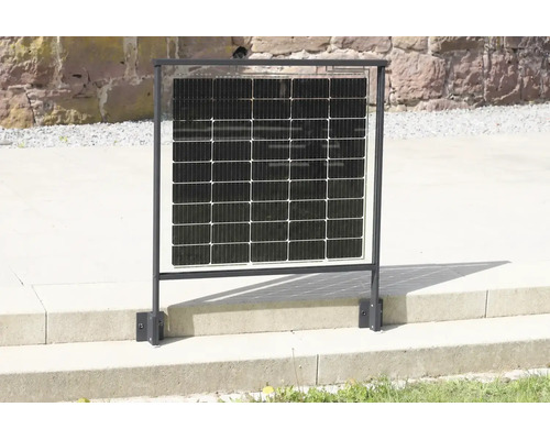 Solární panel integrovaný do černého kovového zábradlí, namontovaný na kamenné terase před zdí z přírodního kamene.