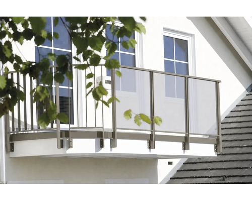 Moderní balkon na bílé fasádě domu se zábradlím z kovových prvků a skleněných výplní.