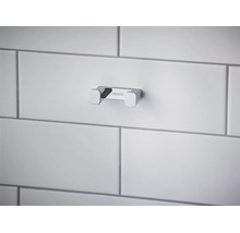 Dvojitý koupelnový háček Hansgrohe z chromovaného kovu, namontovaný na dlážděné stěně.