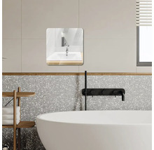 Moderní koupelna se čtvercovým zrcadlem se zaoblenými rohy, bílou vanou, černými bateriemi a stěnami v designu terrazzo.