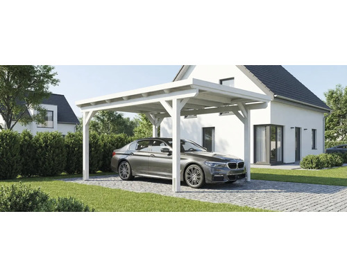 Bílý dřevěný přístřešek pro auto s plochou střechou před moderním bílým domem s parkujícím vozem na dlážděném vjezdu.