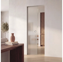 Moderní skleněné posuvné dveře v světlém pokoji, minimalistický design z matného skla s kulatou úchytkou, dřevěná podlaha a bílé stěny.