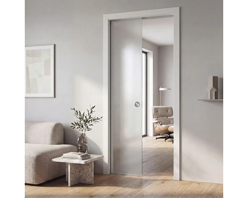 Moderní skleněné posuvné dveře z matného skla s kulatou mušlovou úchytkou, zasazené do světlého minimalistického obývacího pokoje.