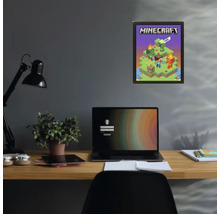 Plakát Minecraft v černém rámu na tmavé stěně nad psacím stolem s notebookem a rostlinou.