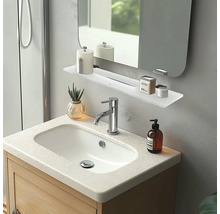 Moderní koupelna s umyvadlovou skříňkou ze světlého dřeva, bílým umyvadlem, chromovanou baterií a bílou skleněnou policí pod zrcadlem.