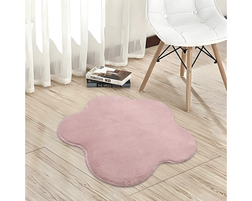 Měkký růžový koberec ve tvaru květiny na světlé dřevěné podlaze vedle židle.