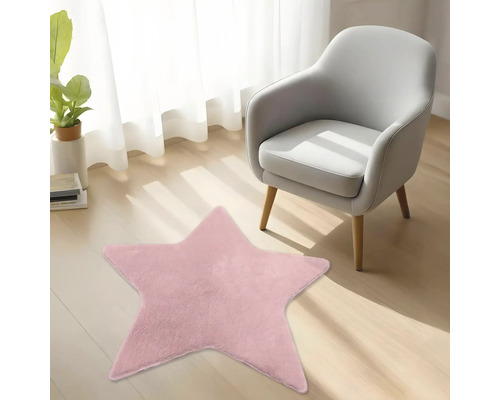 Růžový plyšový koberec ve tvaru hvězdy na dřevěné podlaze vedle moderního křesla ve světlém pokoji.
