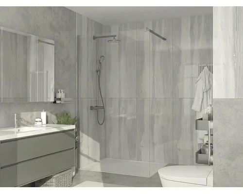 Moderní sprchový kout walk-in se skleněnou stěnou, chromovaným sprchovým systémem, plochou vaničkou a obklady ve světlé koupelně.