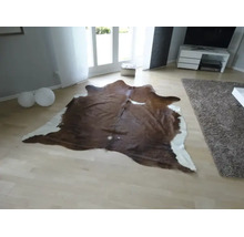Přírodně tvarovaný koberec z hovězí kůže ve světlém, moderně zařízeném obývacím pokoji se světlou parketovou podlahou.