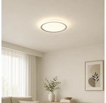Kruhové stropní LED svítidlo ve světlém, moderně zařízeném obývacím pokoji s minimalistickým designem.