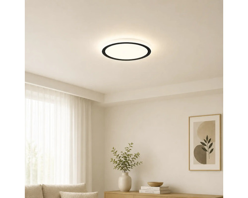 Moderní kulaté stropní LED svítidlo s černým okrajem v světlém, minimalistickém obývacím pokoji s bílými stěnami a světlým nábytkem.
