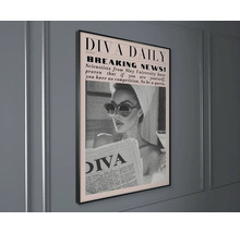 Rámovaný obraz Diva Daily v novinovém stylu, černobílá fotografie ženy se slunečními brýlemi a ručníkem na hlavě.