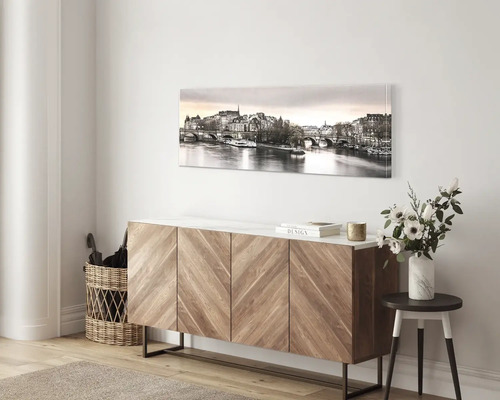 Panoramatický obraz na plátně s pohledem na Paříž nad moderní dřevěnou komodou ve světlém pokoji.