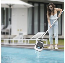 Zena vytahuje bazénový robot Aiper Scuba SE z bazénu pomocí teleskopické tyce na zahrade.