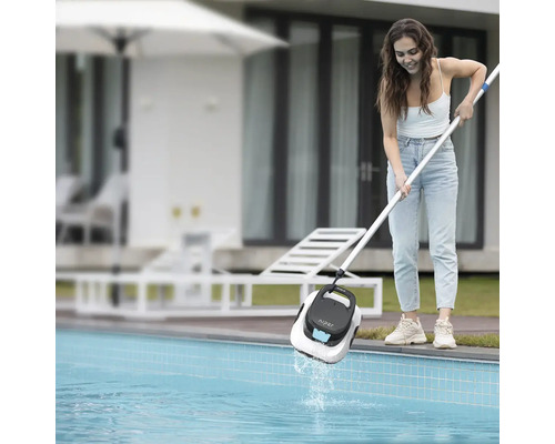 Zena vytahuje bazénový robot Aiper Scuba SE z bazénu pomocí teleskopické tyce na zahrade.